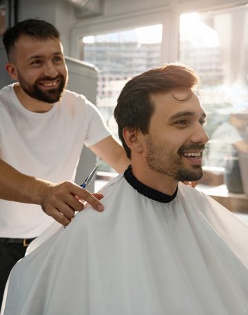 Happy male client of hair salon looking contented with haircut